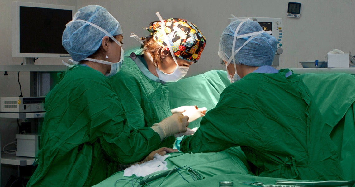 Green medical scrubs, including a top and pants, are displayed alongside a pair of green gloves.