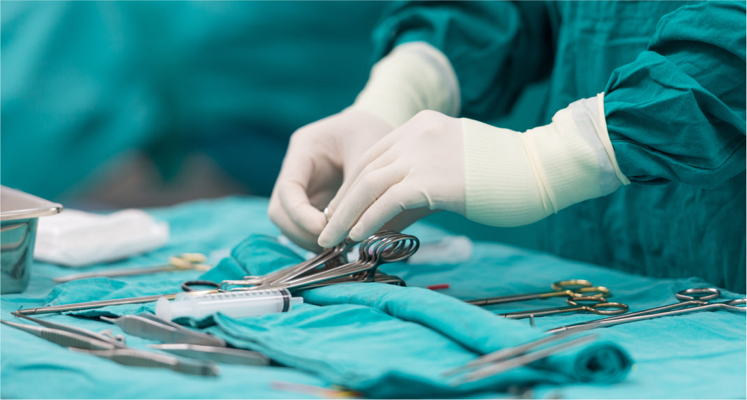 A surgeon's gloved hands arranging surgical instruments on a sterile table, preparing for a medical procedure.