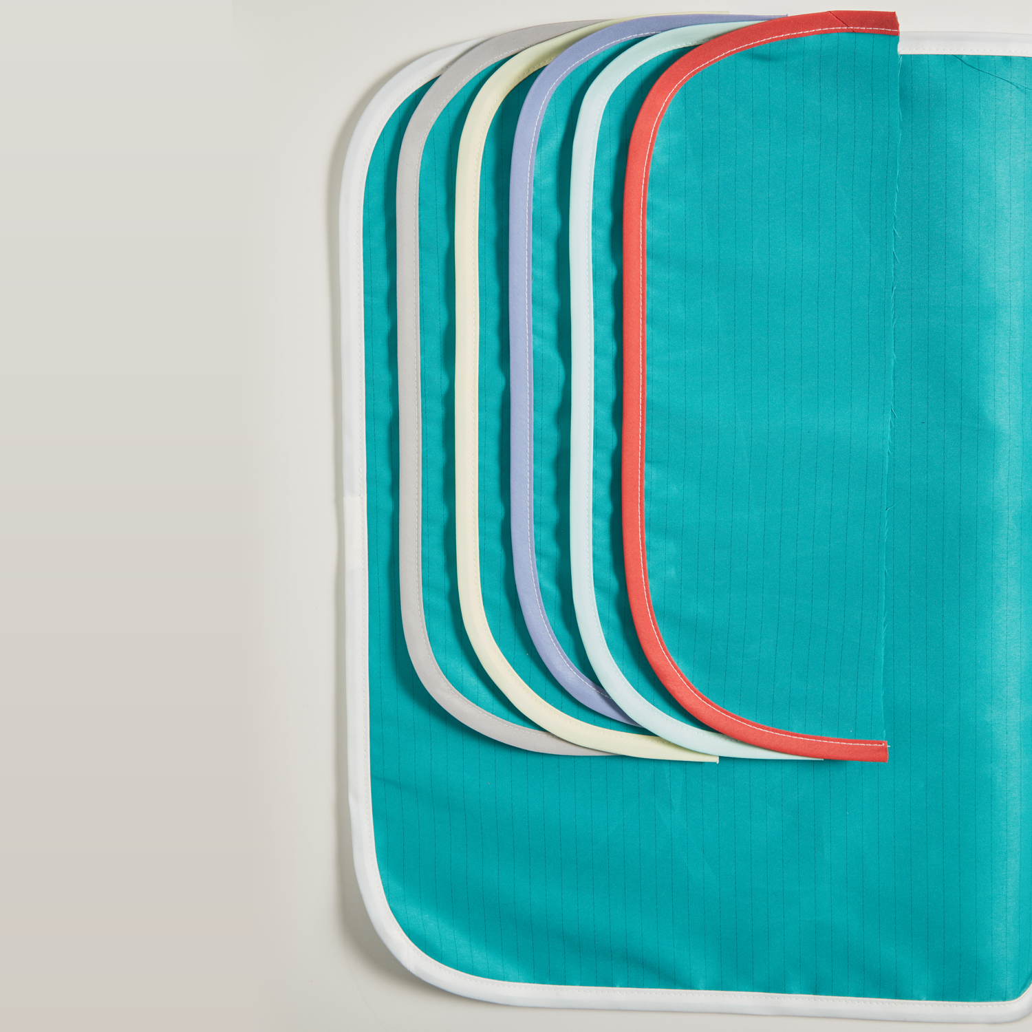 A set of multi-colored, rounded-edge Wrappers, Level 2, Single Ply, Bias Edge made by Lac-Mac, Limited is partially stacked together on a teal background.
